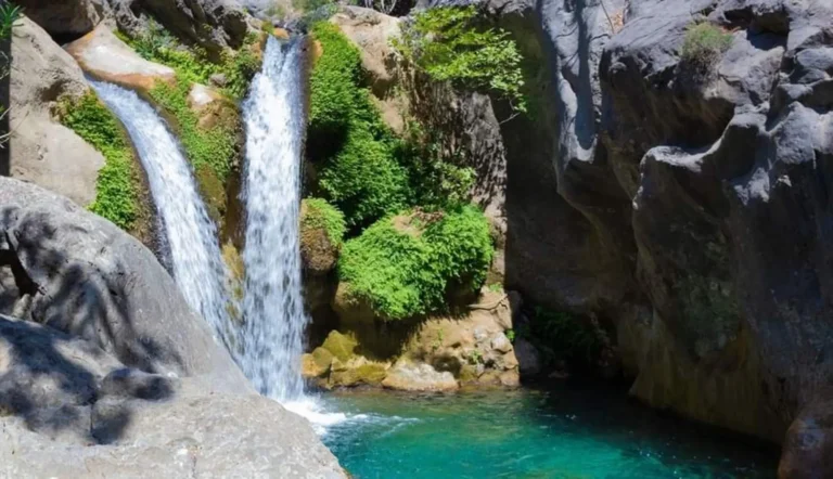Twin waterfall pouring into a turquoise pool between grey rocks in Sapadere Canyon