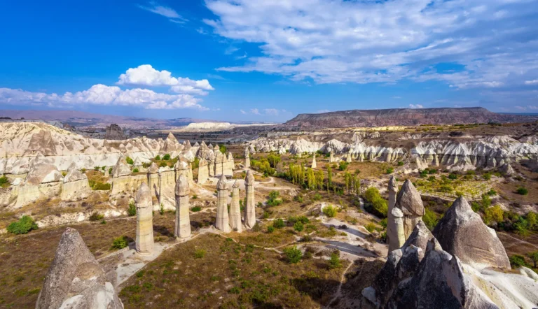 Tall fairy chimneys and green trees in Love Valley under a blue sky