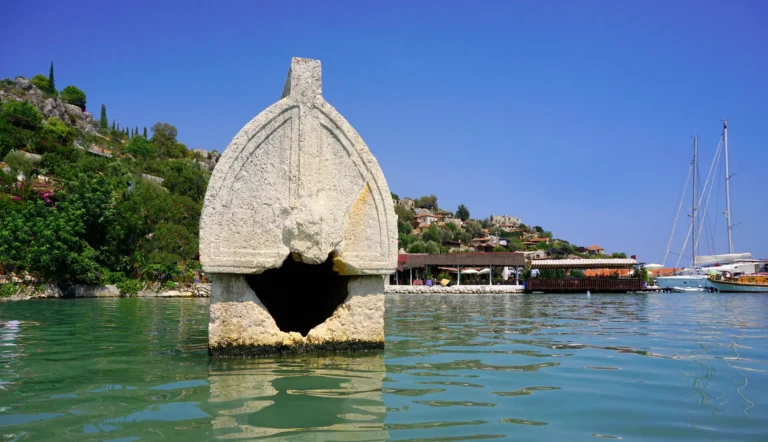 Lycian sarcophagus standing in shallow green water at Kekova