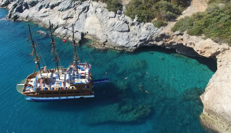 Guests swim from the catamaran into a clear rocky cove beside a cave