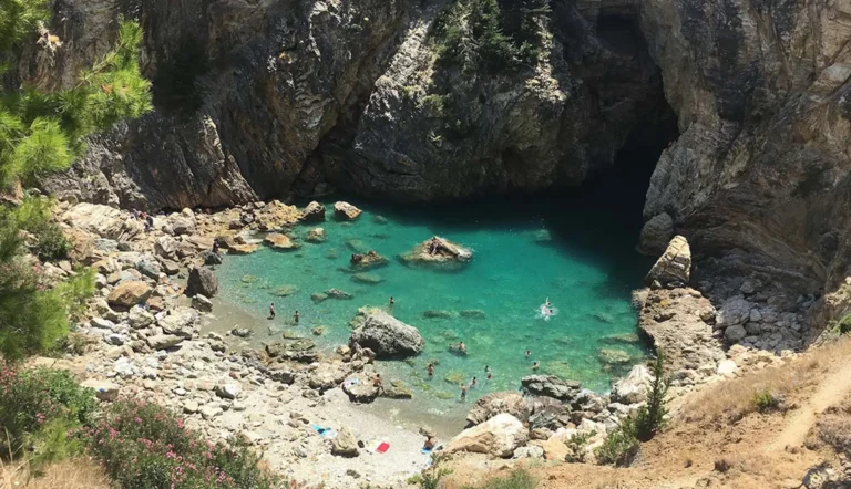 Guests swim in the green lagoon below the cliffs of Delik Sea