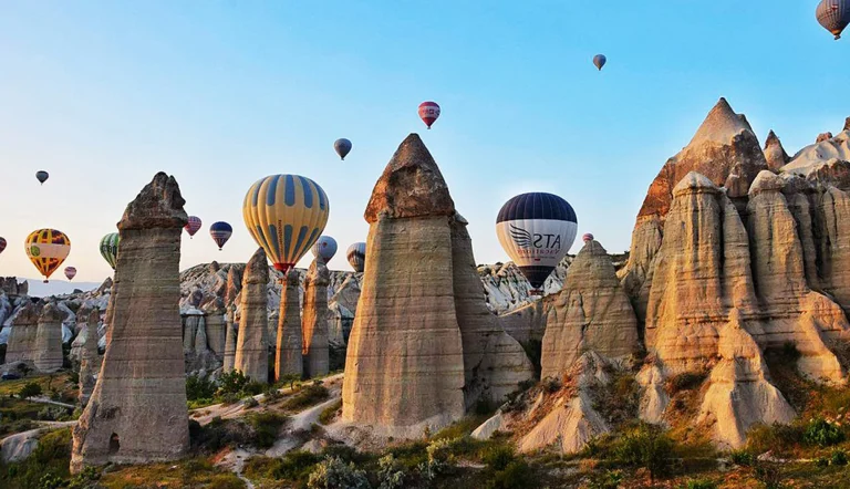 Tall fairy chimneys of Love Valley with balloons drifting in the morning sky