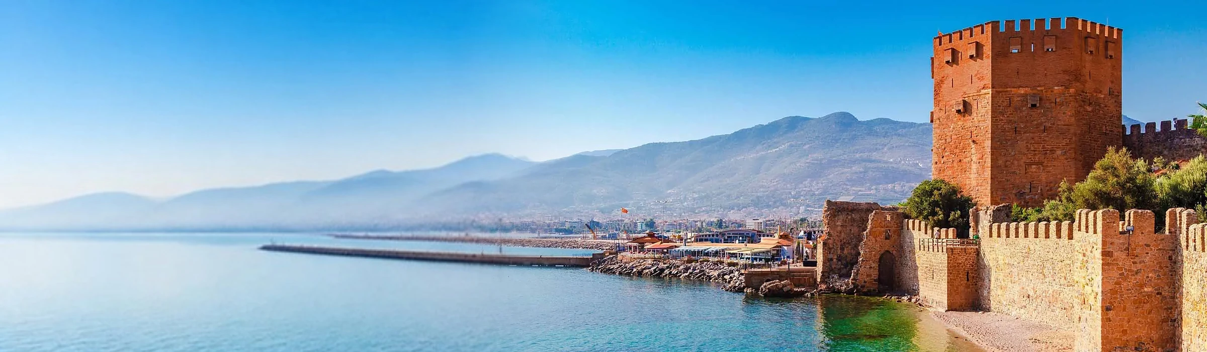 The Red Tower and castle walls on the Alanya harbour with the Taurus mountains